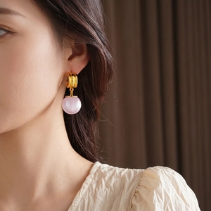 Elegant gold hoop earrings with soft pink resin charms shown on model in a side view