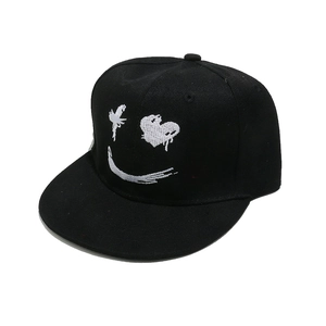 Dettaglio del ricamo a forma di sorriso bianco su un cappellino hip hop nero a tesa piatta