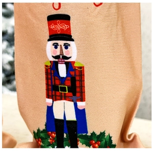 Detail of a Christmas nutcracker soldier print on beige textured fabric wine bottle cover