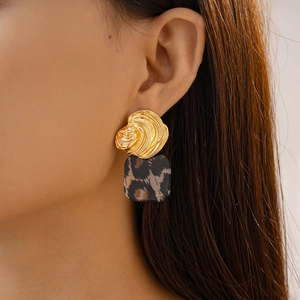 Close-up of leopard print acrylic earrings with gold pleated metal on a model's ear