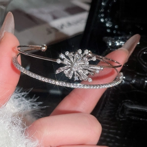Close-up of silver open bangle featuring sparkling zirconia snowflake and elegant pearls
