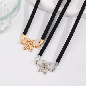 Close-up of gold and silver snowflake pendants on black velvet ribbons with small diamonds