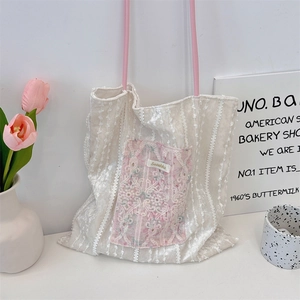 Detailed close-up of cream canvas tote bag with pink floral pocket and white lace trim