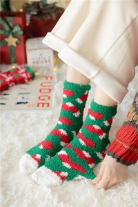 Christmas coral fleece socks with festive patterns shown in a cozy winter setting