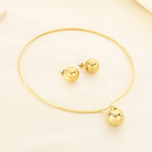 Detail view of gold metal necklace collar and matching spherical earrings on beige fabric