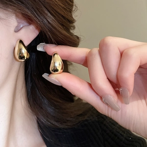 Gros plan de boucles d'oreilles goutte d'eau dorées montrant le style et la taille