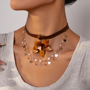 Close-up of vintage choker with amber flower pendant, butterfly charms and gold tassels