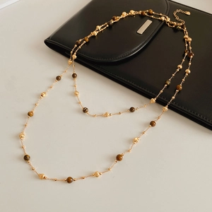 Double-layered gold plated necklace with tiger eye beads on black leather wallet