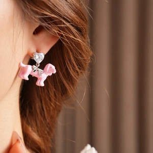 Close-up of heart zircon earring with pink enamel dog pendant and silver bow detail