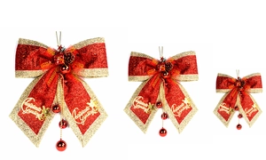 Three red and gold Christmas bows in varied sizes with pine cones and berries