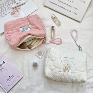 Detail of quilted heart embroidery on soft pink and white cartoon makeup bags