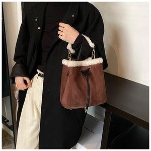 Detail of suede bucket bag featuring white faux shearling trim and drawstring closure