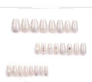 Detail view of nude press-on nails featuring silver celestial star and moon patterns