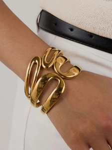 Close-up of a 18k gold plated stainless steel spring cuff bracelet on a model wrist