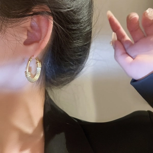 Close-up of golden hoop earrings with woven texture and smooth metal finish on ear