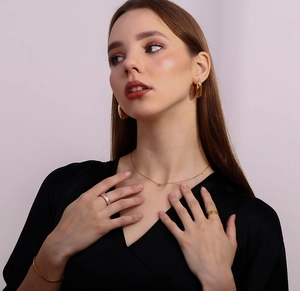 Close-up of thin 18K gold-plated necklace, zircon ring, and bracelet set on model
