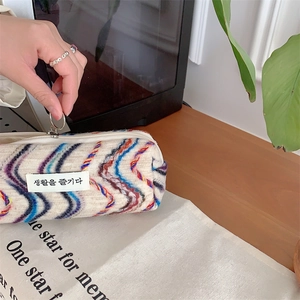 Vue détaillée de la broderie arc-en-ciel sur trousse de toilette avec zip à anneau