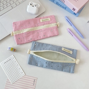 Detail of pink and blue star pattern pencil cases with metal zippers on a study desk
