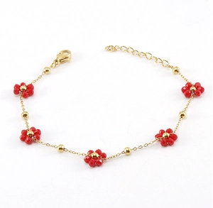 Detail of gold chain bracelet with delicate red flower charms and lobster clasp on white