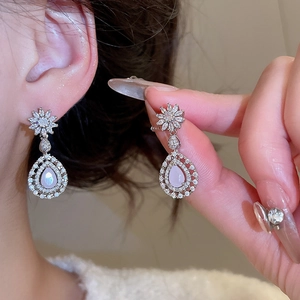 Gros plan de boucles d'oreilles fleur en zircon avec pendentifs goutte rose