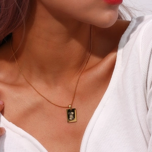 Macro view of 18K gold plated rectangular pendant featuring sun and hand engraving
