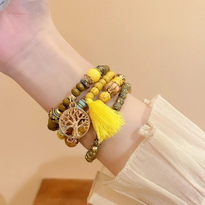 Detail of bohemian multilayer sandalwood beaded bracelet with tree of life charm and tassel