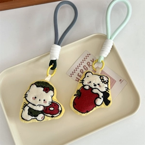 Detail of plush cat charms featuring donut and apple designs with braided lanyards
