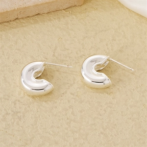 Polished silver C-shaped stud earrings displayed on a textured stone background