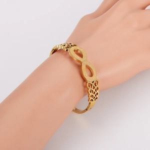 Gold stainless steel infinity bangle with matte finish and hollow pattern on wrist