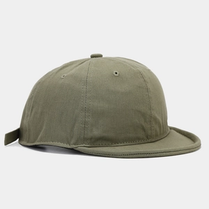 Dettaglio cappellino a visiera corta verde oliva con trama twill e occhielli in metallo