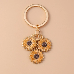Close-up of golden sunflower charms on a keychain with vibrant yellow enamel petals