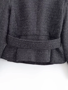 Macro shot of tweed jacket hem and matching belt showing high-quality woven texture