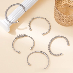 Detailed close-up of textured stainless steel open bangles set with spiral and wave designs