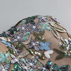 Close-up of intricate floral sequin embroidery on green mesh for elegant evening dresses