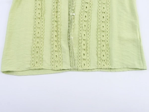 Detail of light green blouse featuring lace inserts, pearl buttons and crinkle texture