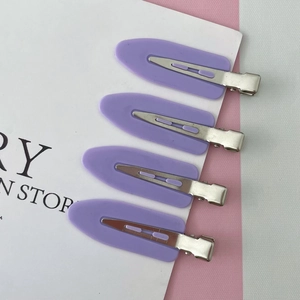 Détail de quatre pinces à cheveux sans trace en violet mat avec base en métal sur carte