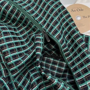 Detail of green plaid tote bag fabric with high-quality black metal zipper closure