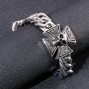 Detail of silver punk skull and cross chain bracelet wrapped on a black jewelry stand