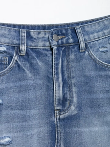 Close-up of distressed denim shorts showing blue wash fabric and ripped hole details