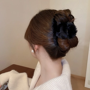 Macro view of large black plush hair claw clip used for an elegant bun hairstyle