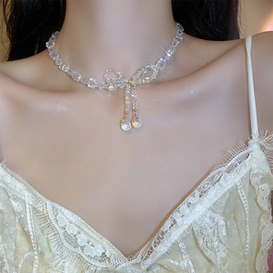 Close-up of crystal bow necklace with teardrop charms on a soft focus model