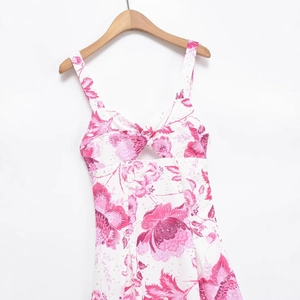 Robe d'été rose à imprimé floral et broderie ajourée sur un cintre en bois