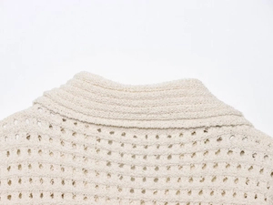 Detailed close-up of cream knit fabric with openwork patterns and textured collar