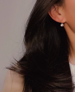 Close-up of 18k gold-plated huggie earring with a sparkling one carat cubic zirconia stone