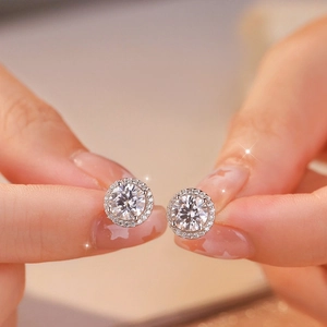 Classic 925 silver moissanite stud earrings with round halo diamonds held by hand