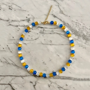 Detail of glacier blue cat eye beads necklace with gold heart pendant and lobster clasp