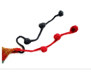 Close-up of winter knit hat featuring decorative navy and red yarn tassels and pom-poms