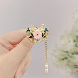 Detailed close-up of a gold lute brooch with pink flowers and a white pearl tassel