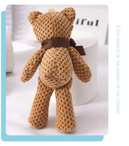 Detail view of a brown knitted teddy bear plush keychain with a silk ribbon bow on back