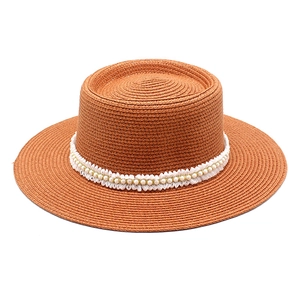 Detailed shot of boater hat with woven straw texture, white lace, and pearl trim